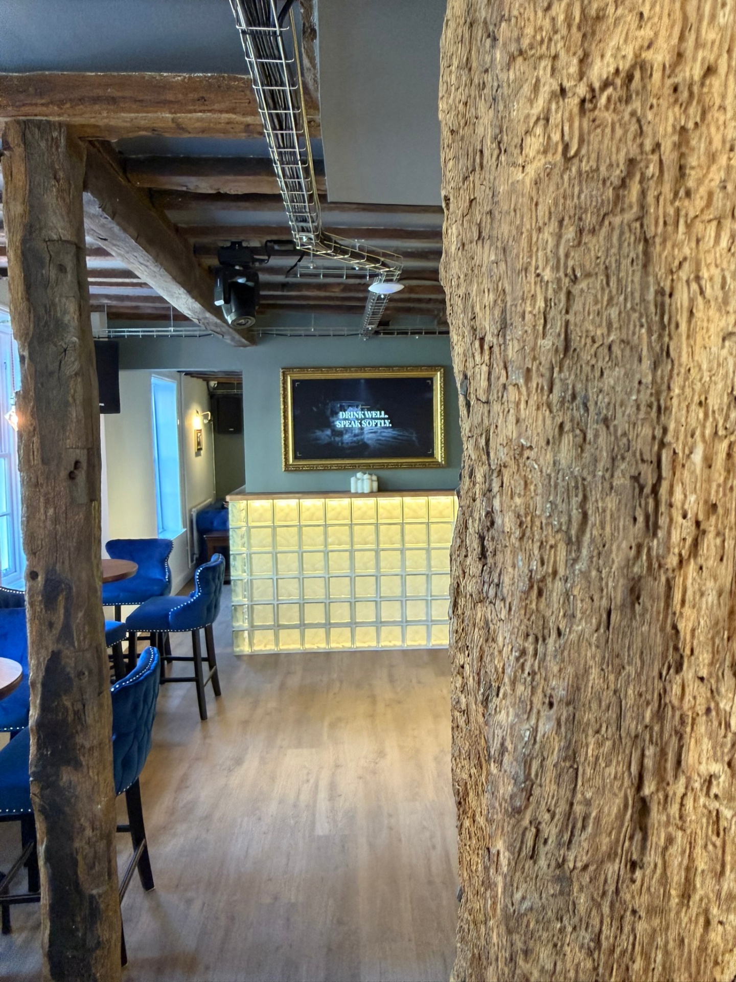 Interior of Hatton Court showing exposed timber beams, glass-brick bar and 'Drink Well, Speak Softly' signage