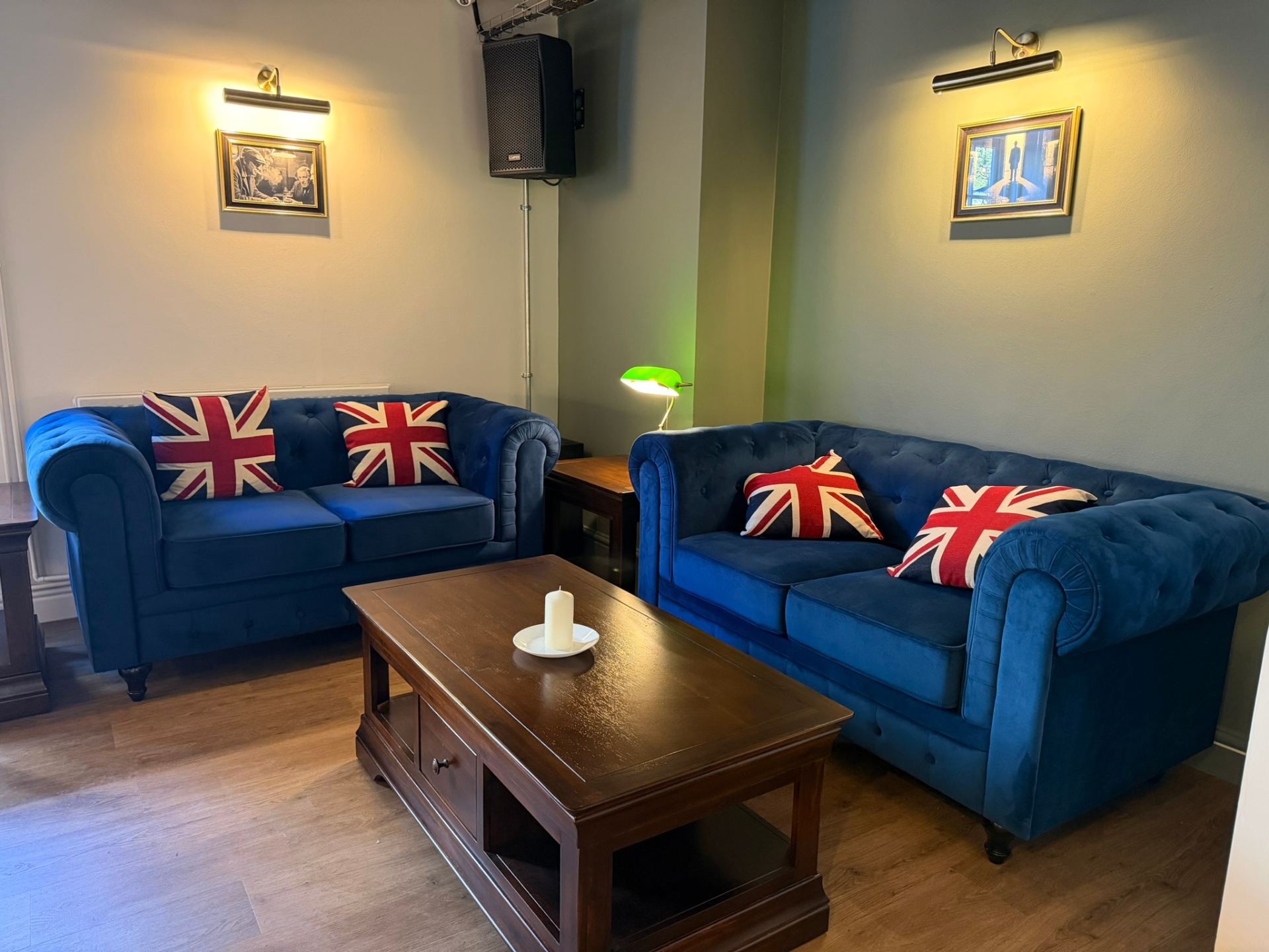 Lounge area at Hatton Court with deep-blue Chesterfield sofas and brass picture lights